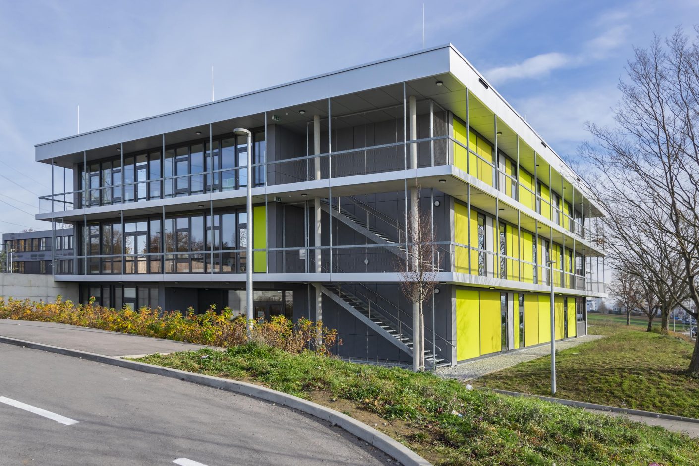 Der Neubau der Theodor-Heuglin-Schule in Ditzingen: Die Fassade ist als Pfosten-Riegel-Konstruktion mit raumhohen Verglasungen und umlaufenden Fluchtbalkonen ausgeführt. Damit der Baukörper bei heruntergefahrenem Sonnenschutz nicht zu massiv wirkt, wählte man textile ZIP-Screens, die farblich mit der Umgebung harmonieren.