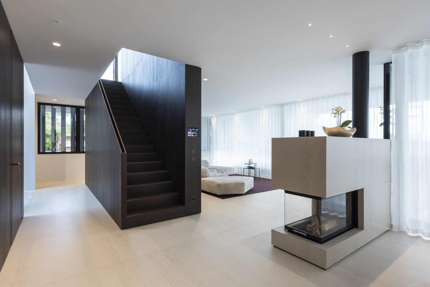 Die Böden im Wohnbereich und auf der Terrasse sind mit sandfarbenen, ca. 140 cm x 140 cm großen Platten aus Dekton Danae ausgelegt (1,2 cm innen, 3 cm außen). © Urheber Schmid Baugruppe Holding GmbH, 2021